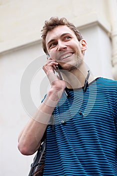 Close up young man smiling and talking with mobile phone outdoors