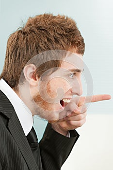 Close-up portrait of young man in suit, pointing and smiling