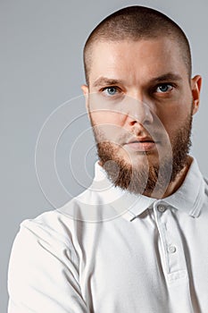 Close-up Portrait of young man in a white T-shirt seriously looking into the frame on a gray background. isolated