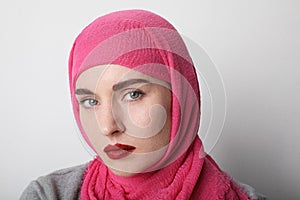 Close-up portrait of a young muslim woman wearing a head scarf hijab and posing over white background. Isolated.