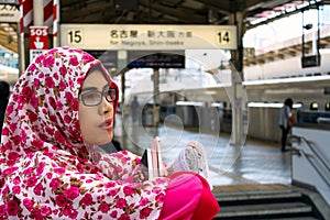Close up portrait of young muslim woman wearing hijab on platform inside Kyoto train station