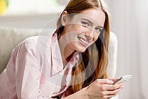 Close up portrait of young pretty smiling woman, holding phone in her hands.