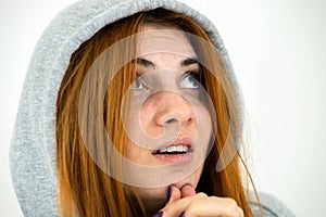Close up portrait of young redhead woman wearing warm hoodie pullover praying holding hands together