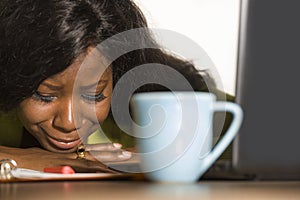 Close up portrait of young sad and depressed black afro American business woman crying while working at office computer desk feeli