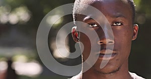 Close up portrait of young serious african american guy looking strictly at camera, posing outdoors, slow motion