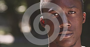 Close up portrait of young serious african american man looking at camera, posing outdoors, slow motion, empty space