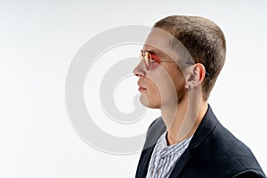 Close up portrait of young serious man in black suit with earring isolated over white background, copyspace for your