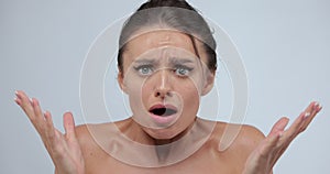 Close-up portrait of young shocked, surprised woman standing isolated over gray background while looking camera. Wow