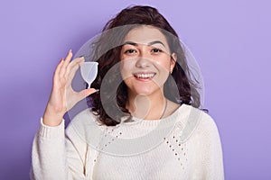 Close up portrait of young smiling beautiful woman holding menstrual cup in one hand, being in good mood, looking directly at