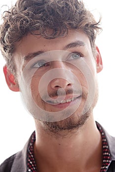 A close-up portrait of a young smiling man looking up and sideways