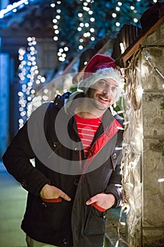 Close up portrait of young smiling man, with santa claus cap sta