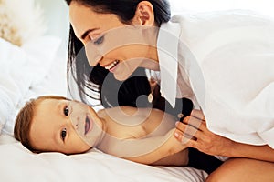 A close-up portrait of a young smiling woman and her sweet baby. A charming mom is playing with her little child