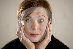 Close up portrait of young sweet and pretty red hair woman looking sad and depressed in dramatic face expression feeling lonely