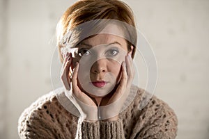 Close up portrait of young sweet and pretty red hair woman looking sad and depressed in dramatic face expression feeling lonely