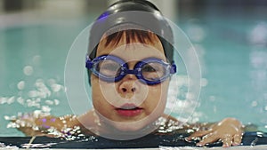 close-up portrait young swimmer boy black swimming cup blue goggles