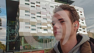 Close up portrait of a young teenager in wireless bluetooth headphones looking aside. Focused and calm gaze, meditates