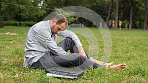 Close-up portrait of young unhappy businessman. He is sitting on a grass.