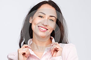 Close-up portrait of a young very beautiful woman with a charming toothy smile, black hair and brown eyes on a white background in