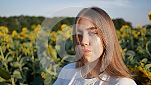 Close-up portrait of young woman agronomist on background of sunflower field