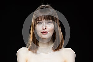 Close-up portrait of a young woman on a black background.