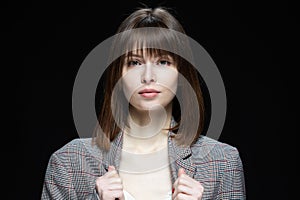 Close-up portrait of a young woman on a black background.