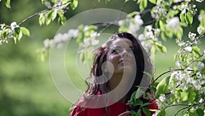 close-up portrait of a young woman enjoying a warm weekend day rad with a tree flowers inhale the fragrance