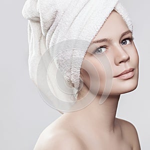 Close-up portrait of young woman with perfect health skin of face and bath towel on head. on white