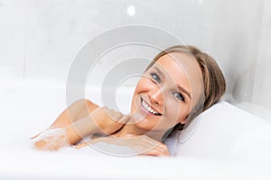 Close-up portrait of a young woman relaxing in the bathtube with smile
