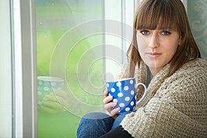 Young Woman Relaxing by Window with Cup of Tea