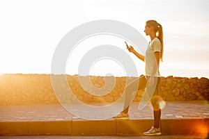 Close-up portrait of young woman in sportswear, holding smartphone, takes selfie in between workouts