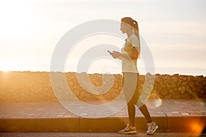 Close-up portrait of young woman in sportswear, holding smartphone, takes selfie in between workouts