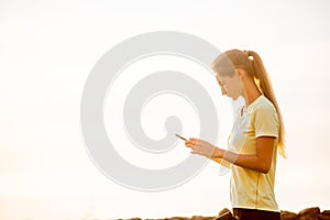 Close-up portrait of young woman in sportswear, holding smartphone, takes selfie in between workouts