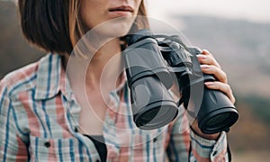Close-up portrait of young woman traveler with binoculars.