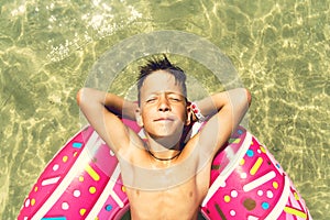 Close up portreit of boy is floating on an inflatable donut ring in the sea. Toned photo