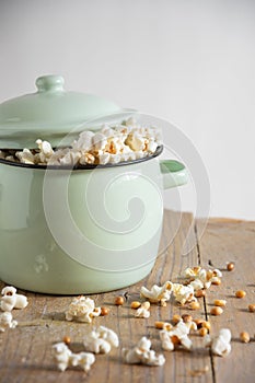 Close-up of pot with fresh popcorn on rustic wooden table, white background