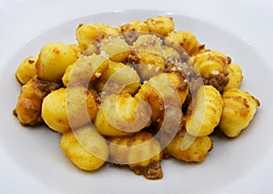 Close-up of potato gnocchi with bolognese sauce ragu on a white plate