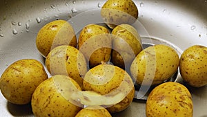 Close up. Potato peelings fall on raw potatoes in the sink