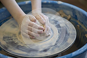 Close-up of a potter`s hands with an item on a potter`s wheel. Working with clay