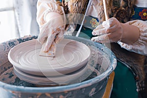 Close-up of the potter`s hands with a wooden spatula to align the plate during the production process