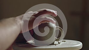 Close up of potter using tools to making ceramic clay bottom of cup in potter studio