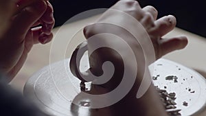 Close up of potter using tools to making ceramic clay bottom of cup in potter studio