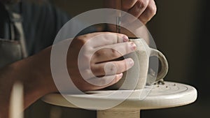 Close up of potter using tools to making ceramic clay cup in potter studio