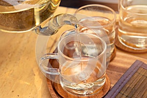 Close up Pour the tea from the kettle into a cup of tea on the table