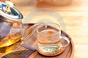 Close up Pour the tea from the kettle into a cup of tea on the table