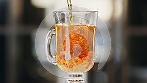 Close up pouring fresh appetizing tea with herb and berry in glass cup. Shot with RED camera in 4K