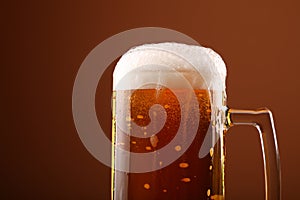 Close up pouring frothy beer in glass over brown