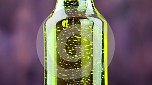 Close-up of pouring olive oil in the bottle on wood background