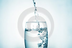 Close up of pouring purified drinking water from a bottle with bubbles and splashes on a white background