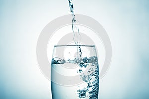 Close up of pouring purified drinking water from a bottle with bubbles and splashes on a white background