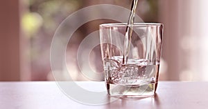 Close up pouring purified fresh drink water from the bottle on a